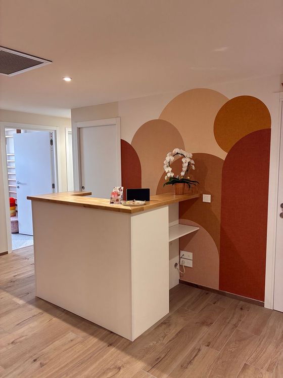 L'accueil du studio : comptoir en bois clair devant une fresque d'arches terracotta.