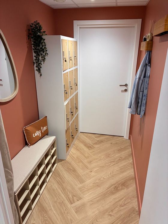 Le vestiaire avec casiers en bois, banc et miroir.